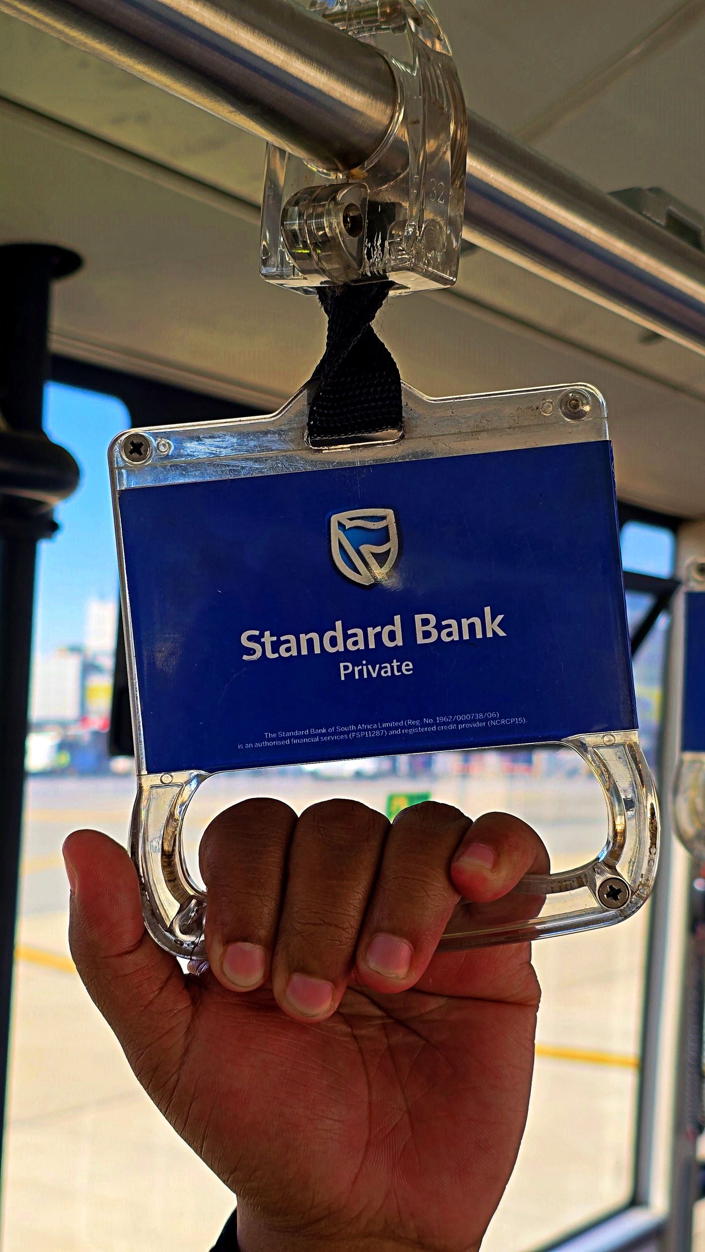 Standard Bank Private branded grab handle held inside an airport bus