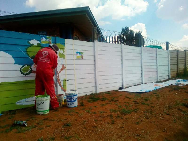 Youth artist painting a community school wall