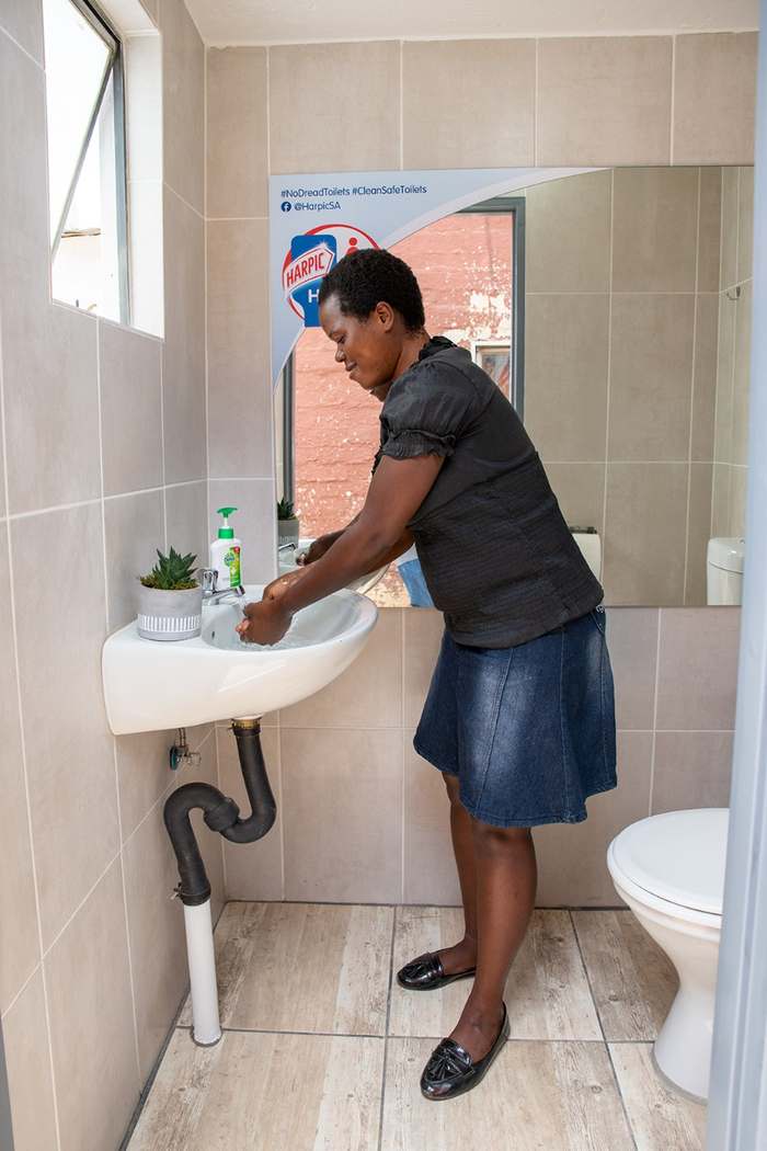 Resident washing her hands at the running-water basin inside the new facility
