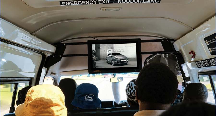 Passengers inside a minibus taxi watching an HD screen