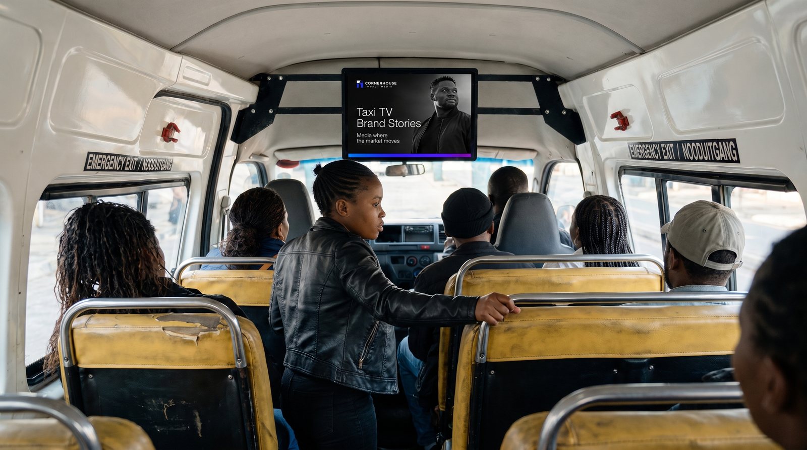 Passengers in a minibus taxi with the Taxi TV screen playing at the front of the cabin